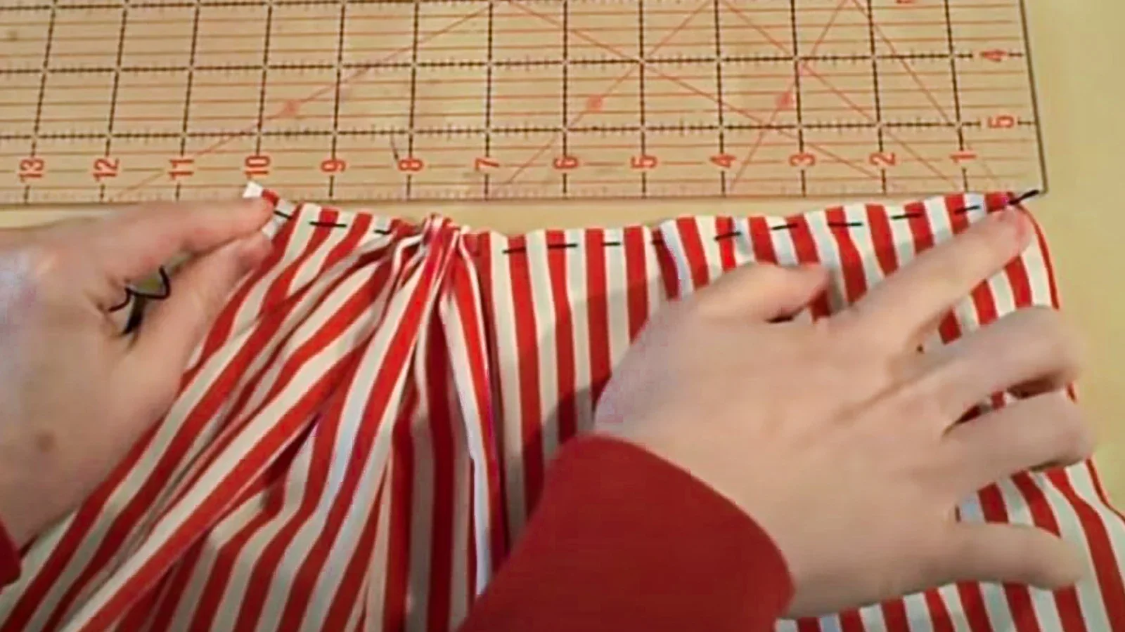 A person cutting a red and white striped skirt.