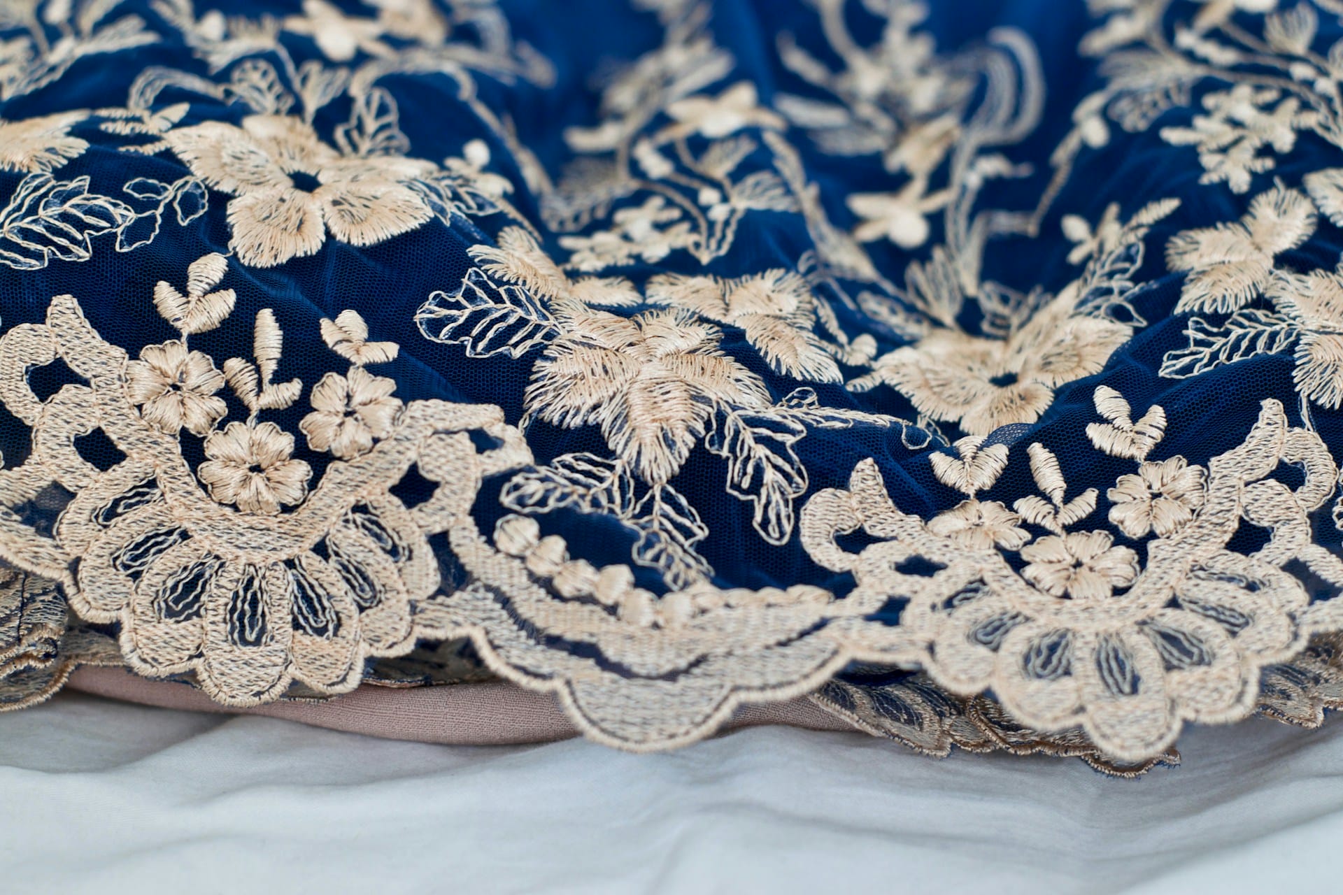 A close up of a blue and beige embroidered lace dress.