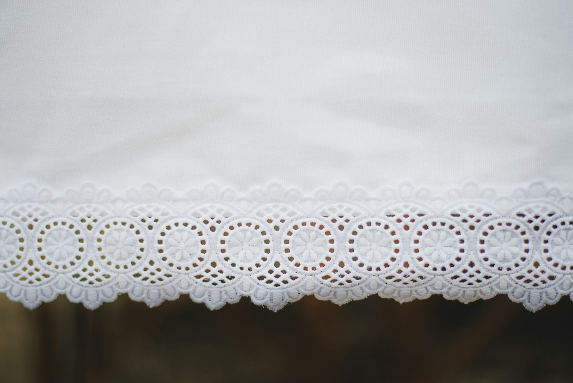 A close up of a white tablecloth with lace on it.