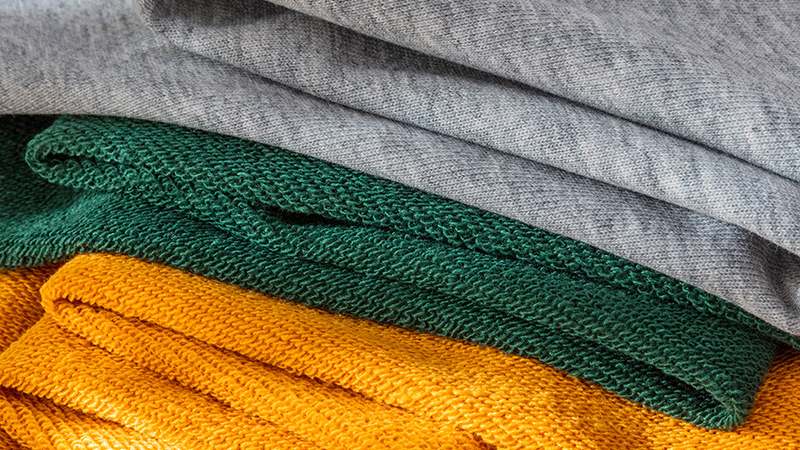 A stack of yellow, green, and grey French Terry