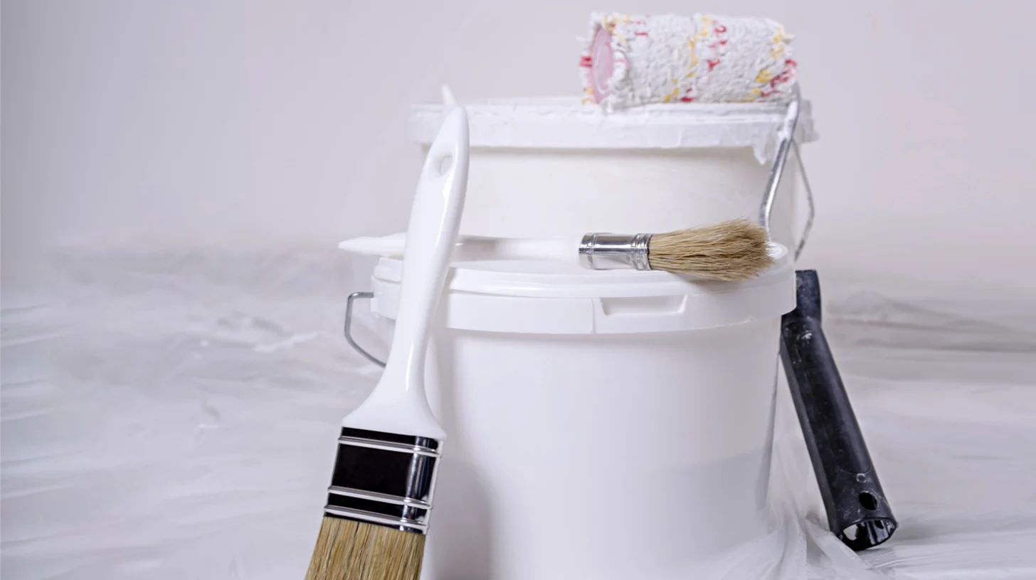 A bucket of paint and a brush on a white background.