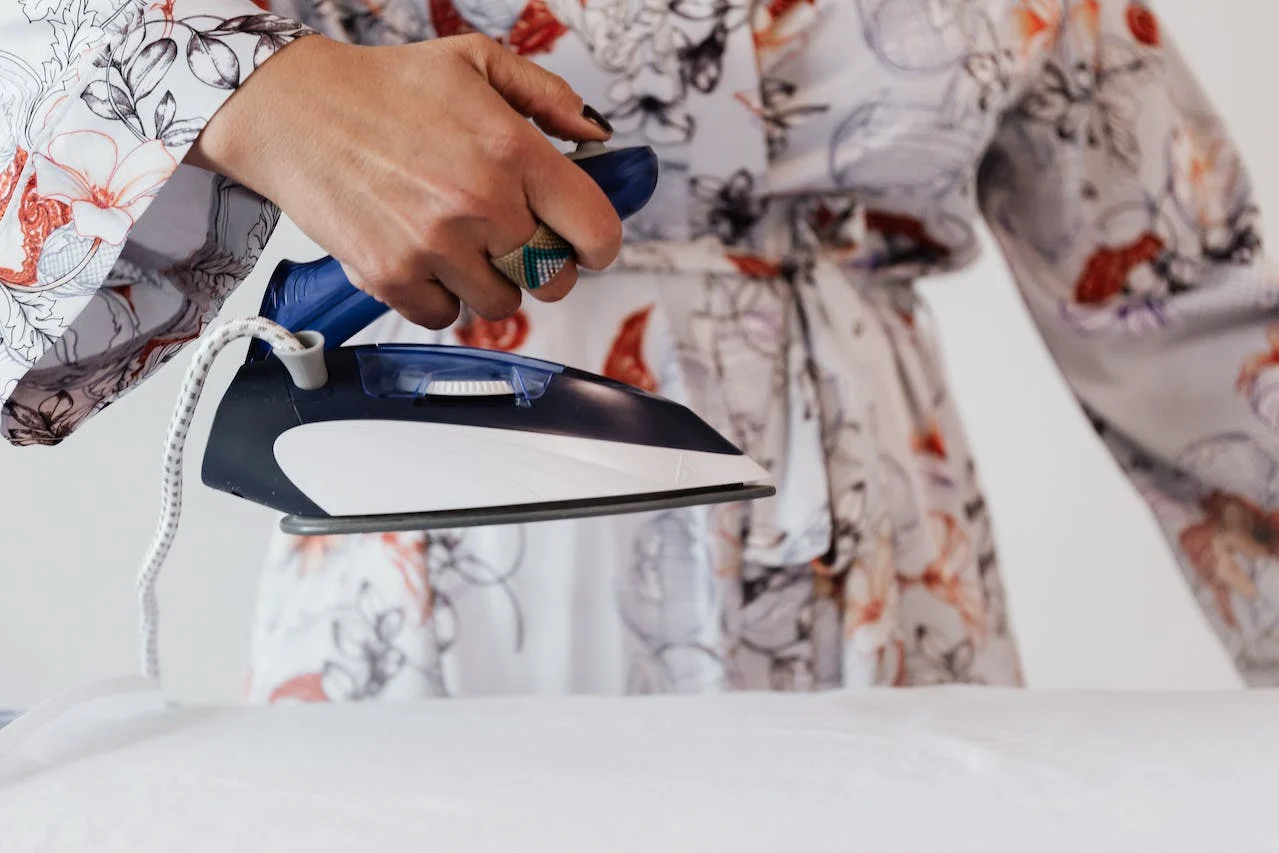 A woman in a floral robe is ironing