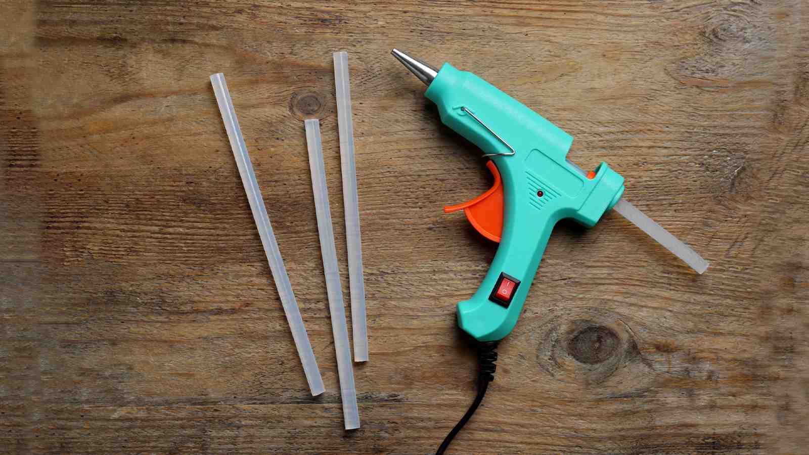 A glue gun with plastic sticks on a wooden table.