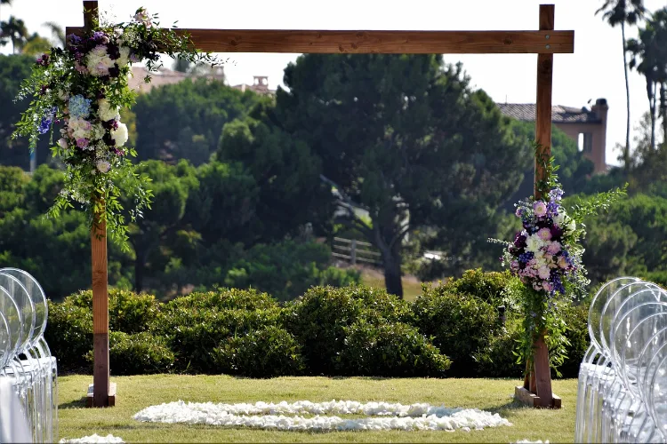 A rustic wedding arch, embellished with some flowers and greenery.