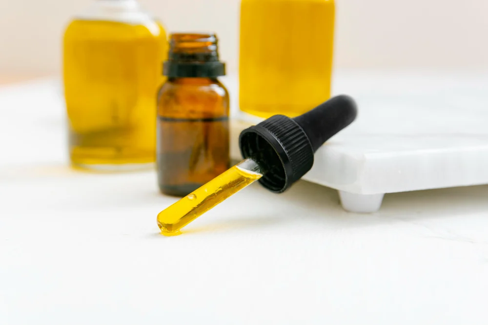 A bottle of essential oil with a dropper on a white surface.