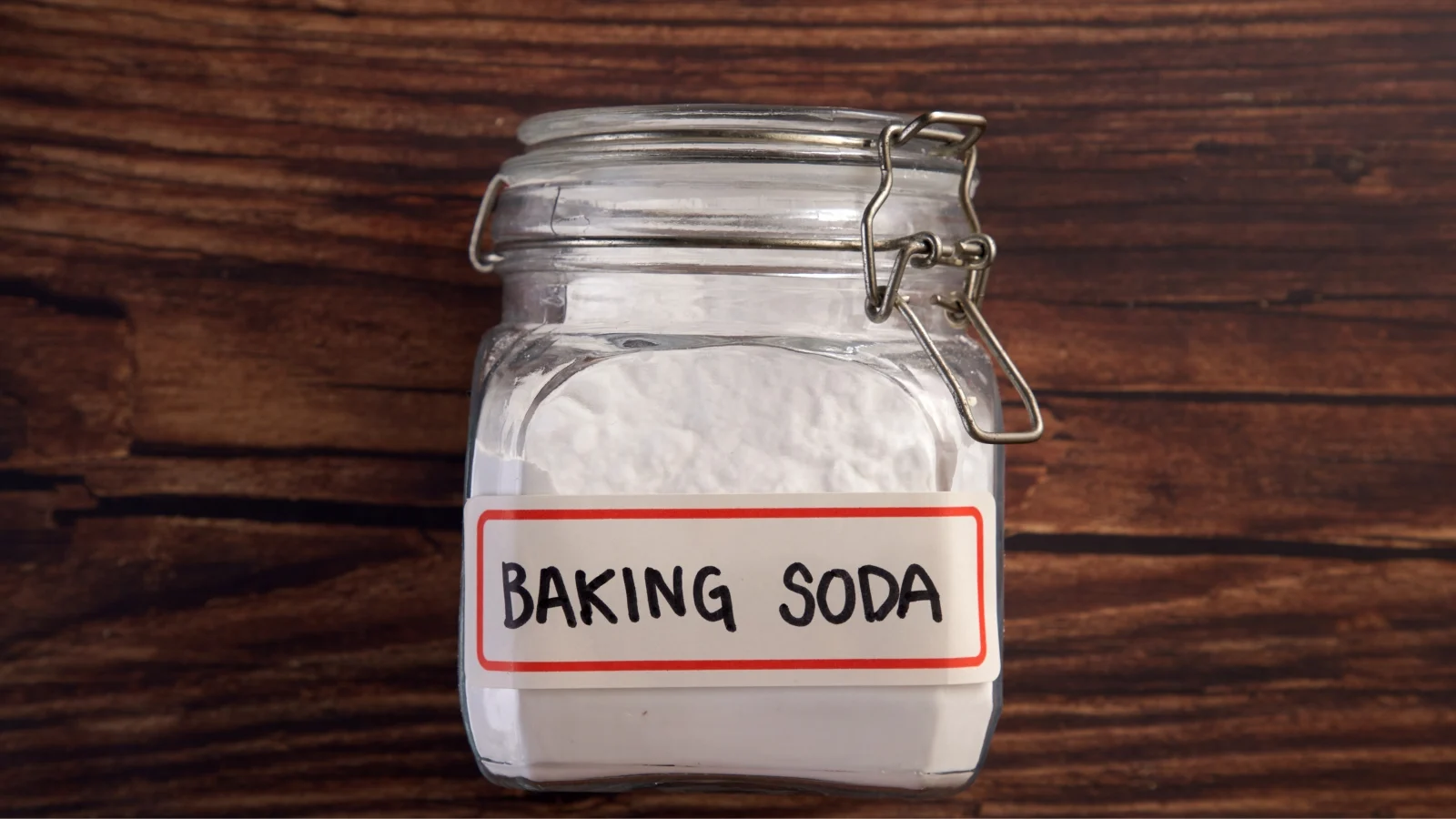 Baking soda in a glass jar on a wooden table.