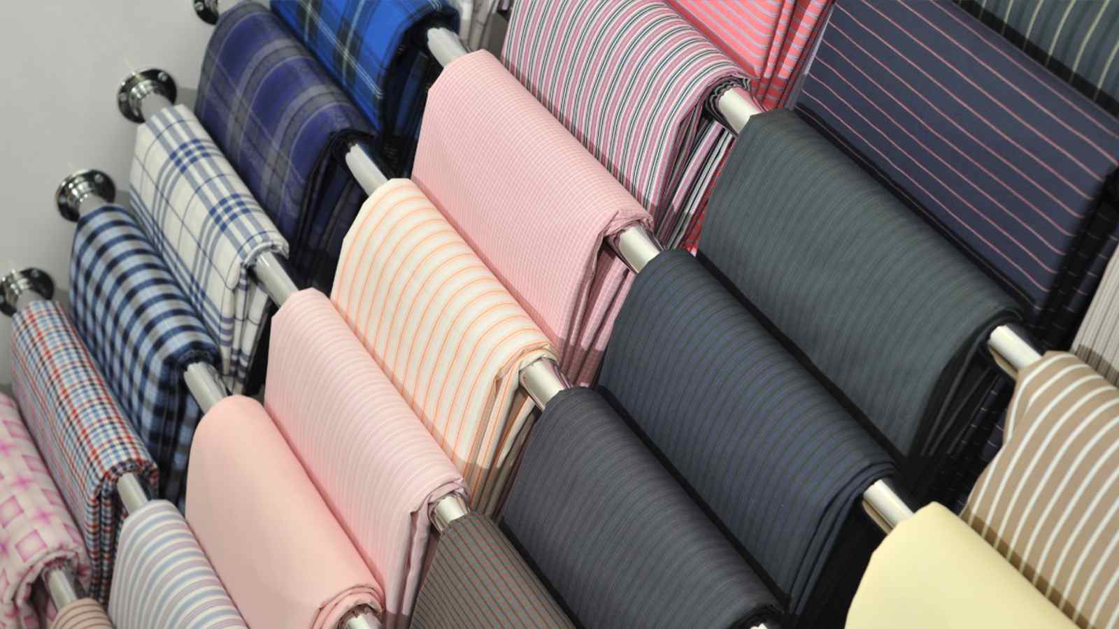 A row of different colored fabris on a rack.