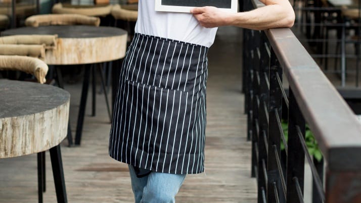 A man in a striped apron holding a board.
