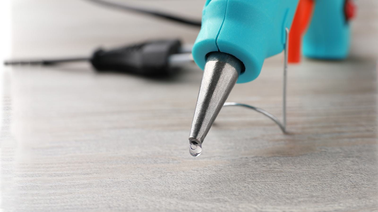 A blue electric hot glue gun on a wooden table.