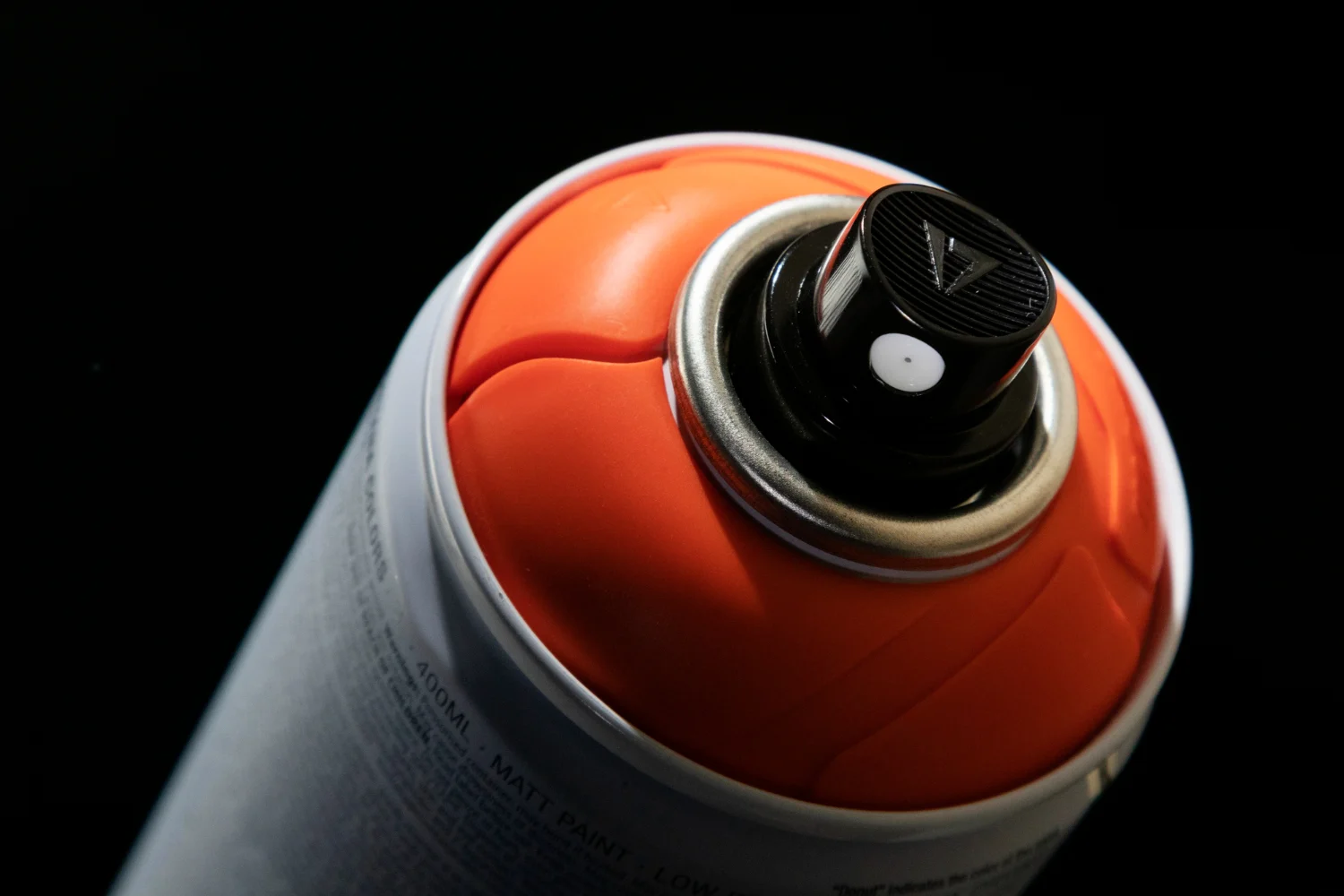 A close up of an orange spray bottle on a black background.