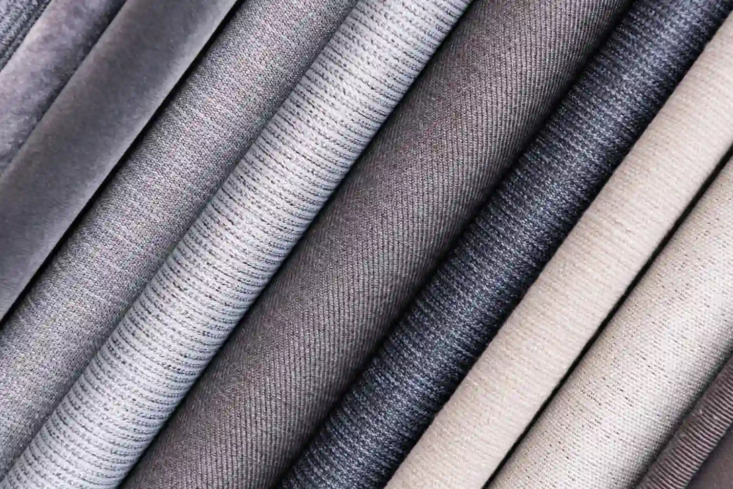 A close up view of a variety of gray polyester fabrics.