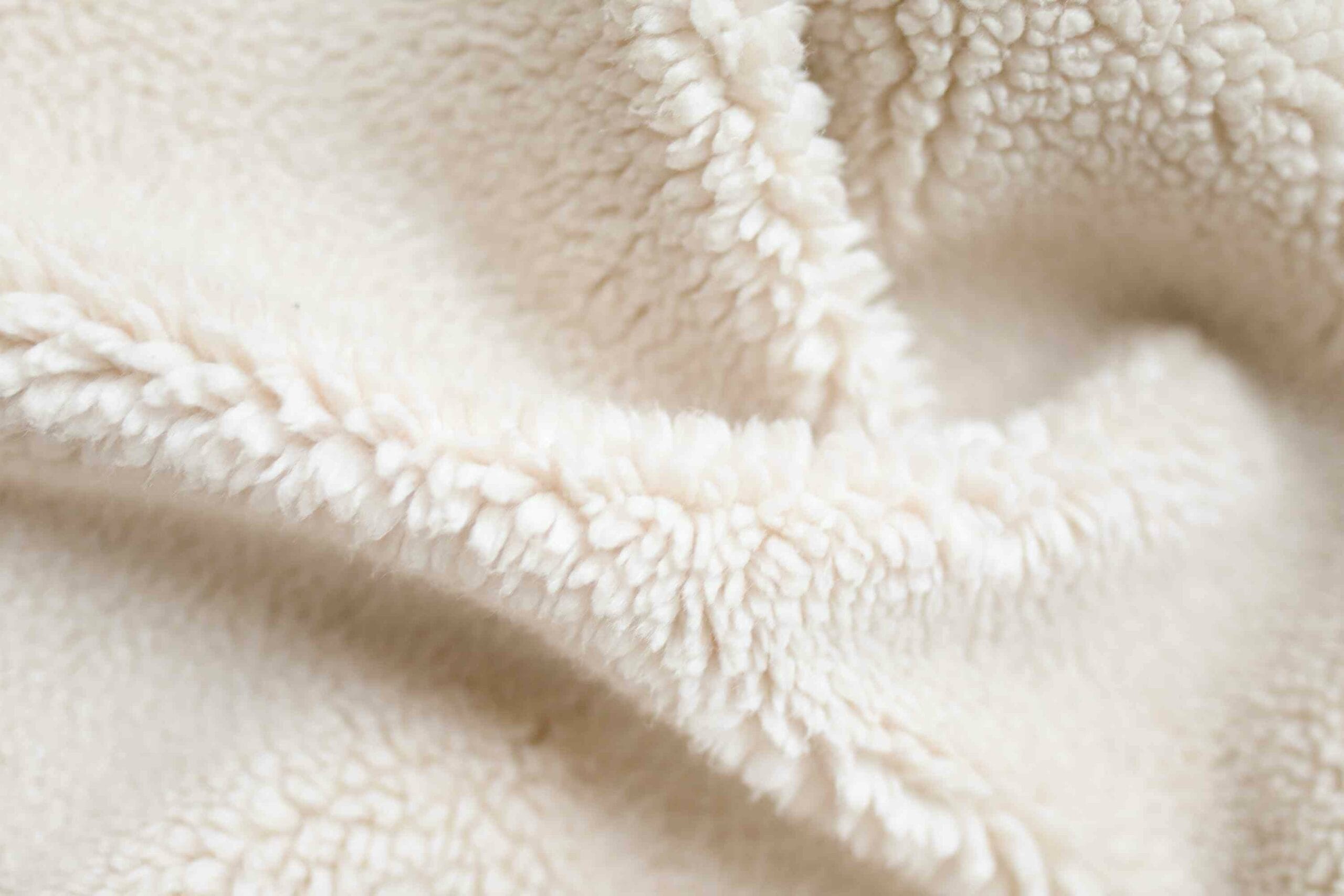 A close up of a white sherpa fleece fabric.