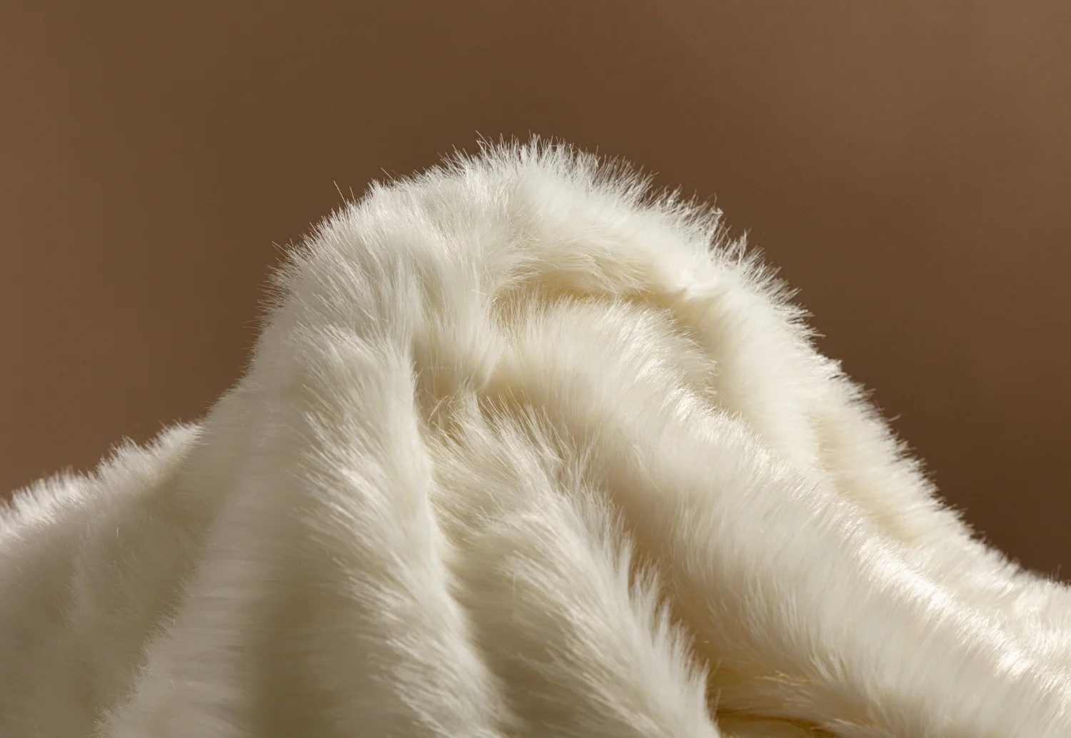 A close up of a white fur fabric on a brown background.